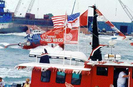 Julie Anne (partially obscured by flag), surfing the wakes of bigger boats